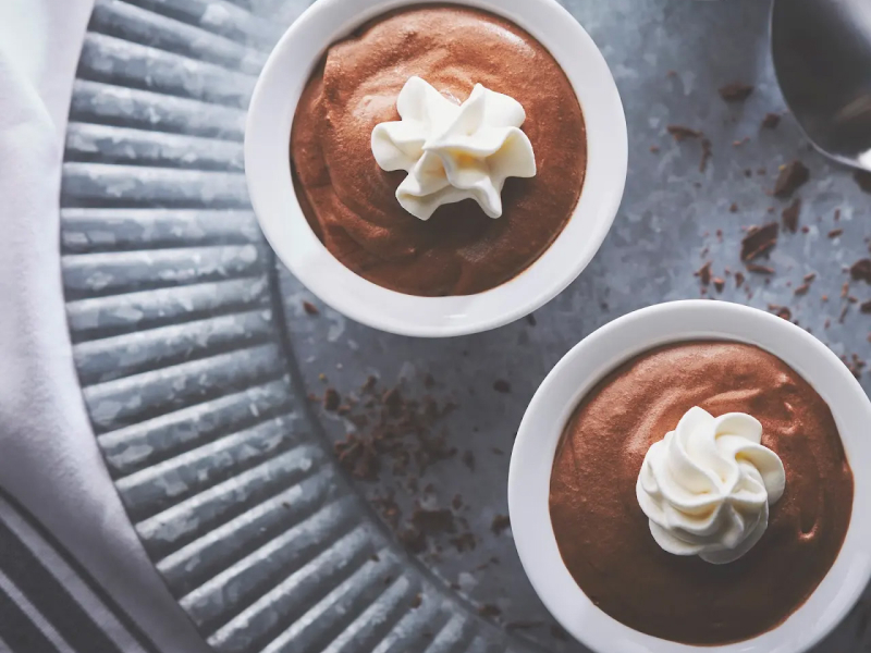 Chocolate mousse in white ramekins with whipped cream