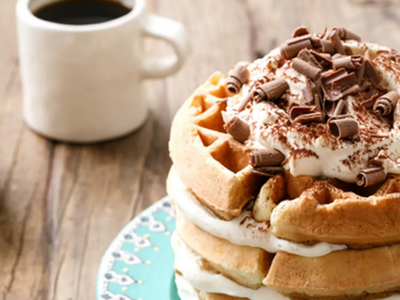 Waffle cake garnished with whipped cream and chocolate curls
