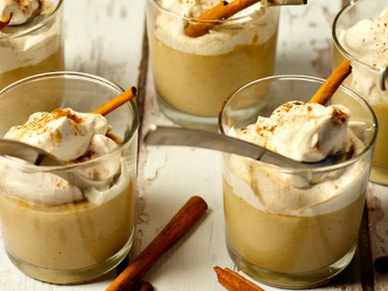 Individual puddings in glass mugs garnished with whipped cream and cinnamon