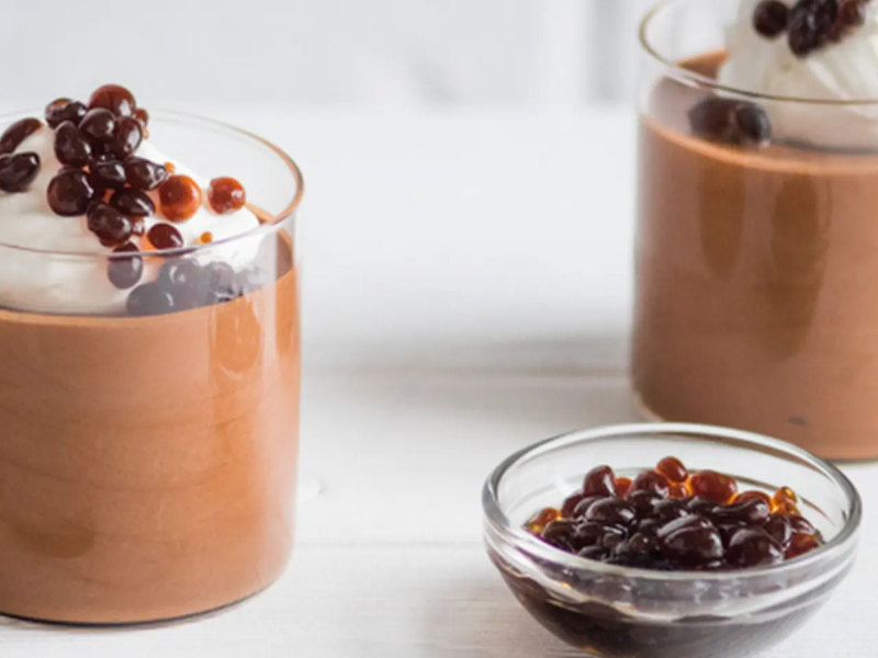 Individual chocolate mousse desserts with whipped cream and espresso caviar