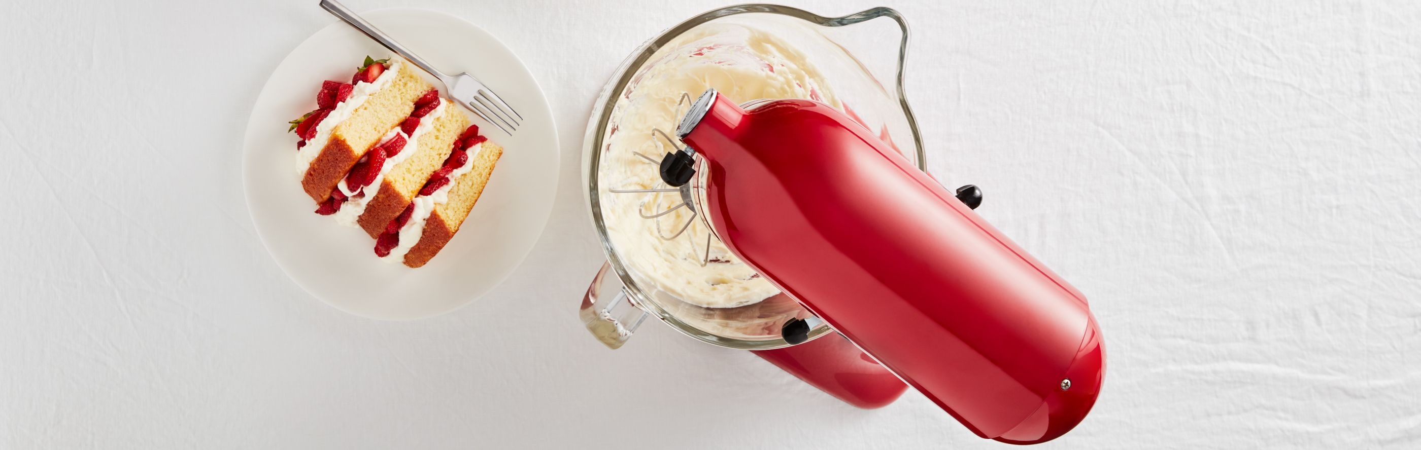 A red KitchenAid® stand mixer and a plate of strawberry shortcake.