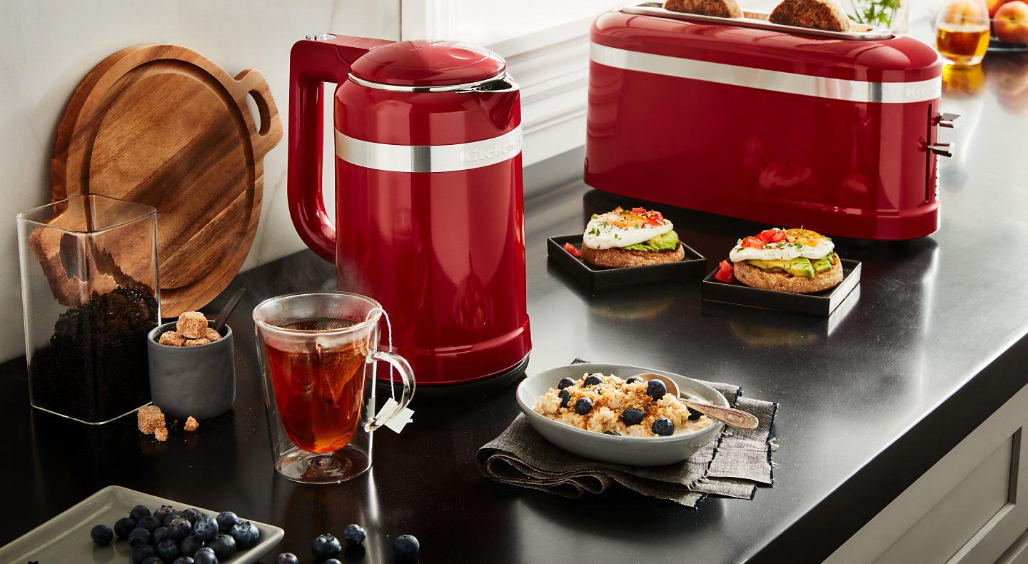 Red KitchenAid® electric kettle next to a cup of tea and breakfast bowl