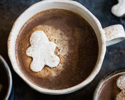 A cup of spiked gingerbread hot cocoa with a marshmallow man