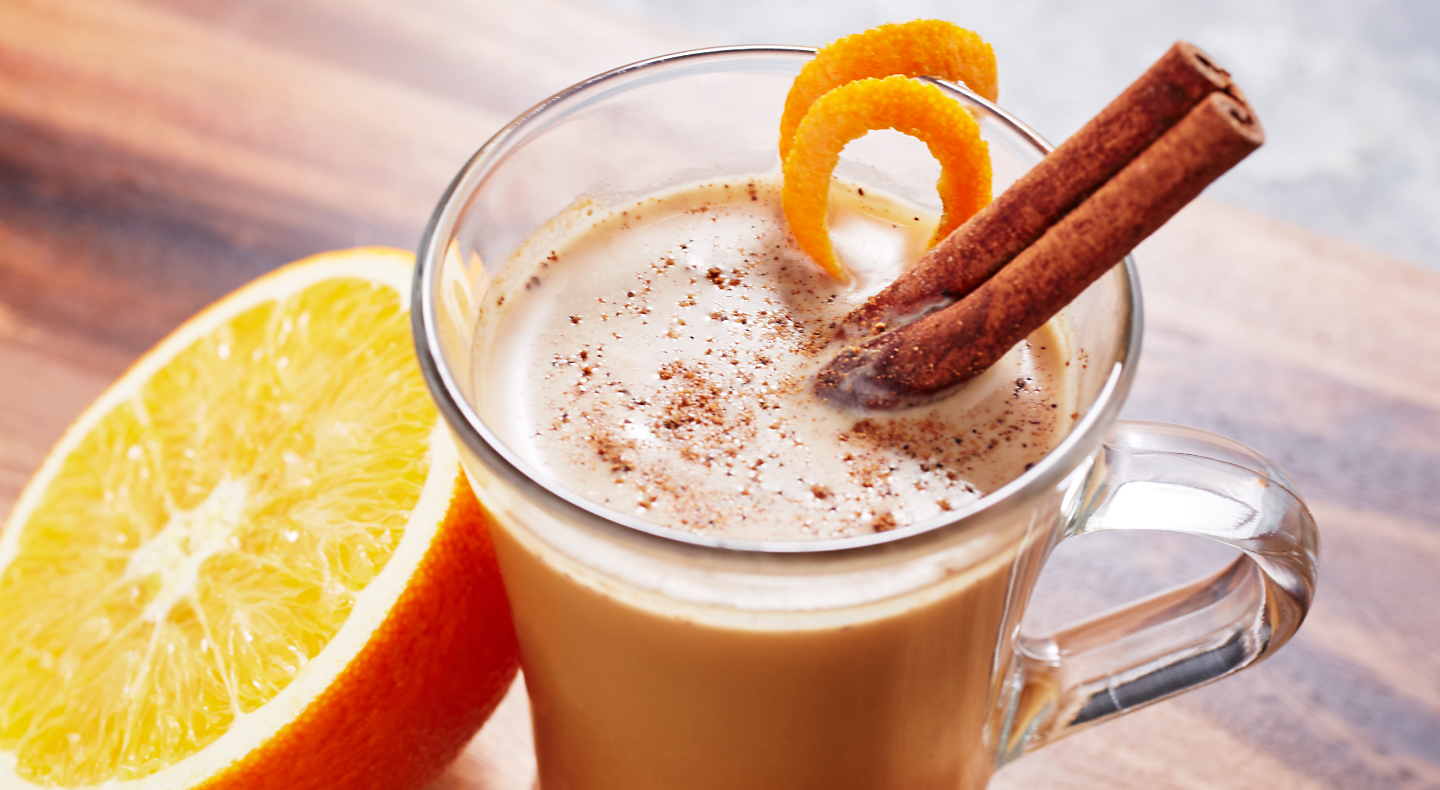 A glass of citrus cafe ole with cinnamon sticks