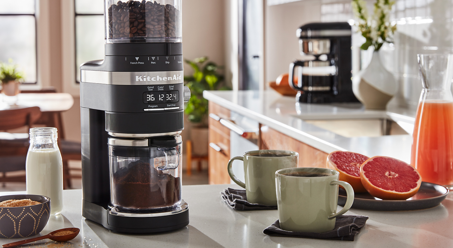 KitchenAid® burr grinder next to two coffee mugs