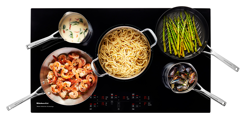 Five pieces of cookware filled with shrimp, asparagus, mussels, spaghetti noodles and sauce