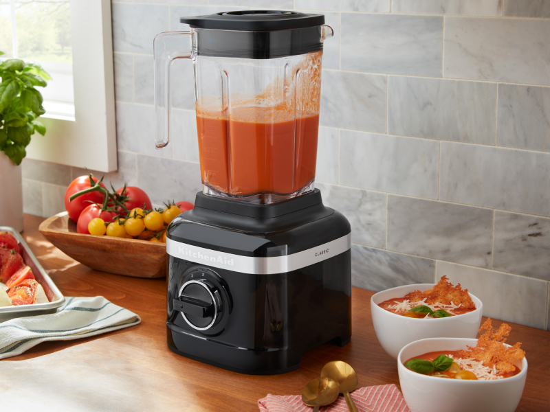 A KitchenAid® blender with freshly pureed soup ingredients on a modern kitchen counter.