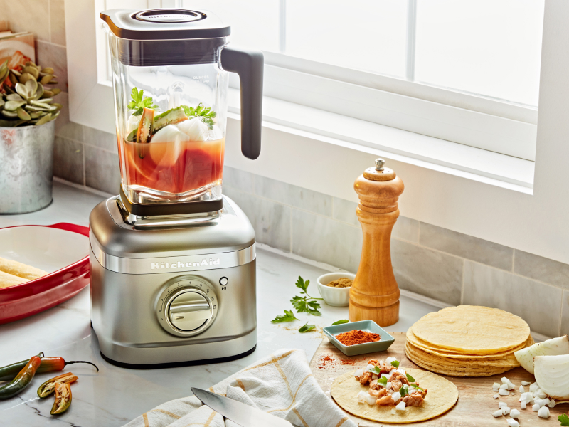 A KitchenAid® blender with chopped vegetables on a modern kitchen counter