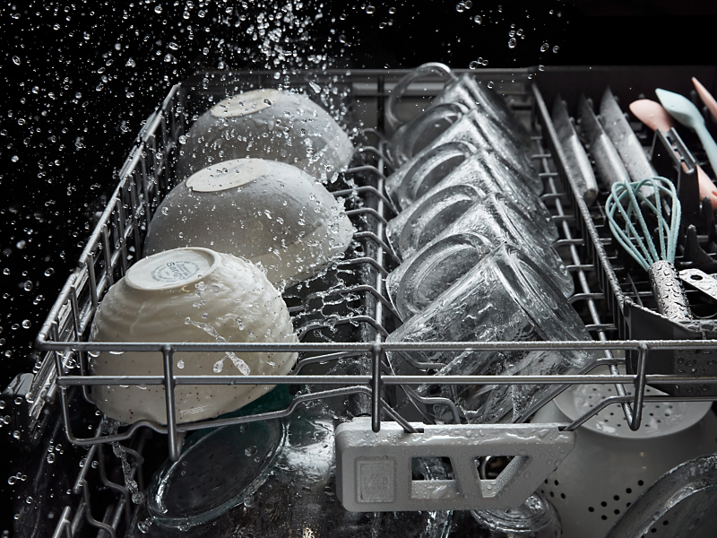 Dishes and glassware being washed inside a dishwasher