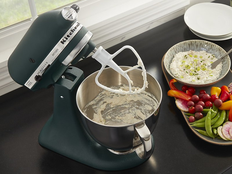 Black KitchenAid brand stand mixer with a flat beater making dip