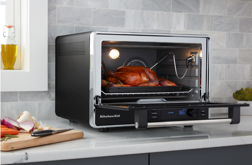 A KitchenAid® countertop oven with a roasted turkey inside.