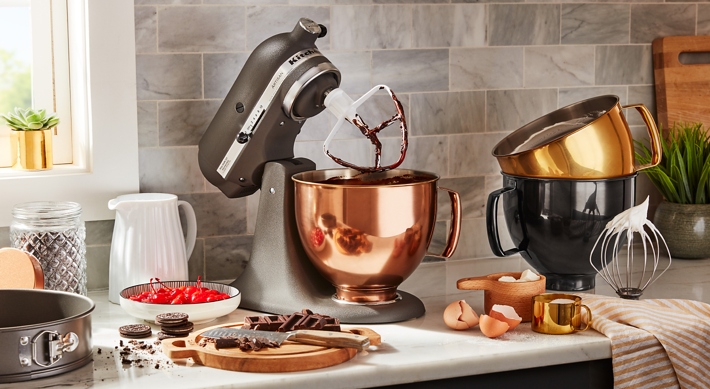A KitchenAid® stand mixer and various metallic mixing bowls