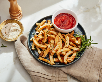 Herb garnished french fries on a plate with dip
