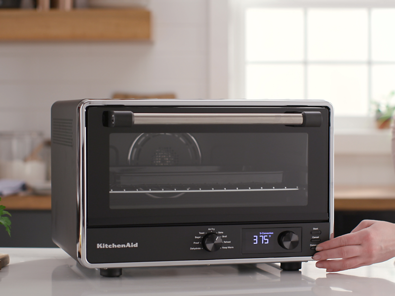 Person setting controls on a KitchenAid® countertop oven