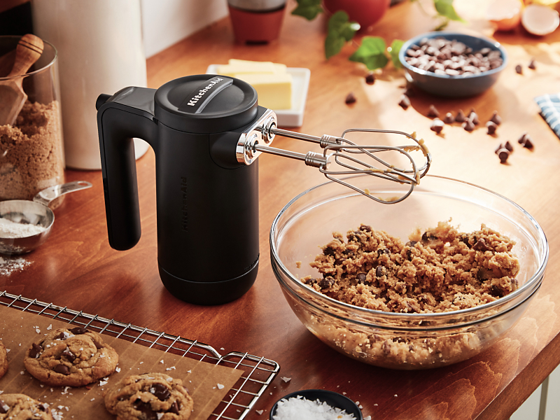 Black KitchenAid® hand mixer with beaters over cookie dough