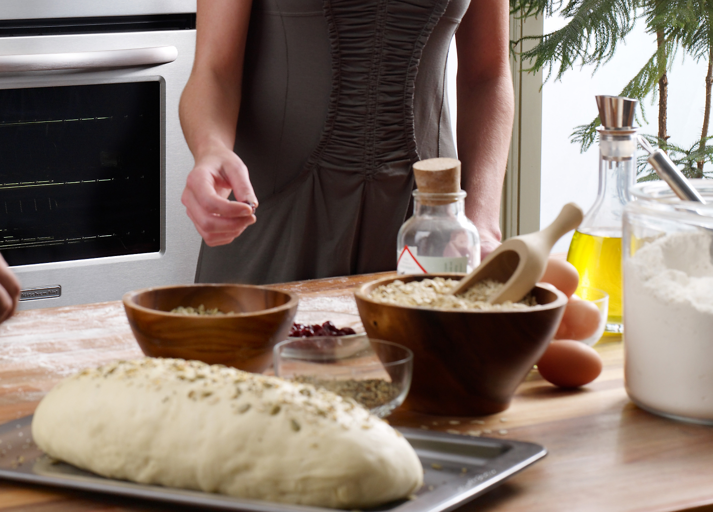 A woman adding spices to a loaf of bread dough that’s ready to go into the oven.