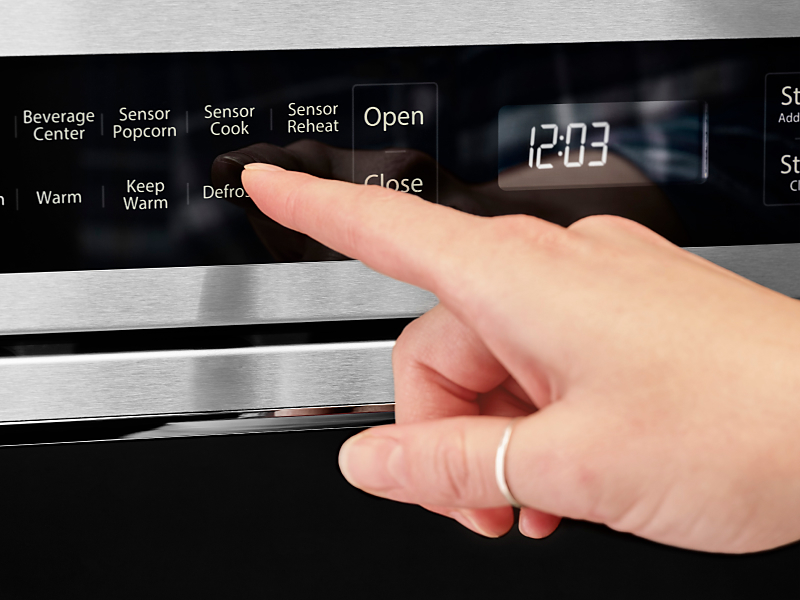 Person using the defrost option on a KitchenAid® microwave