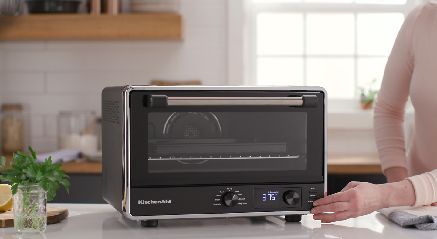 Person pressing setting on KitchenAid® countertop oven