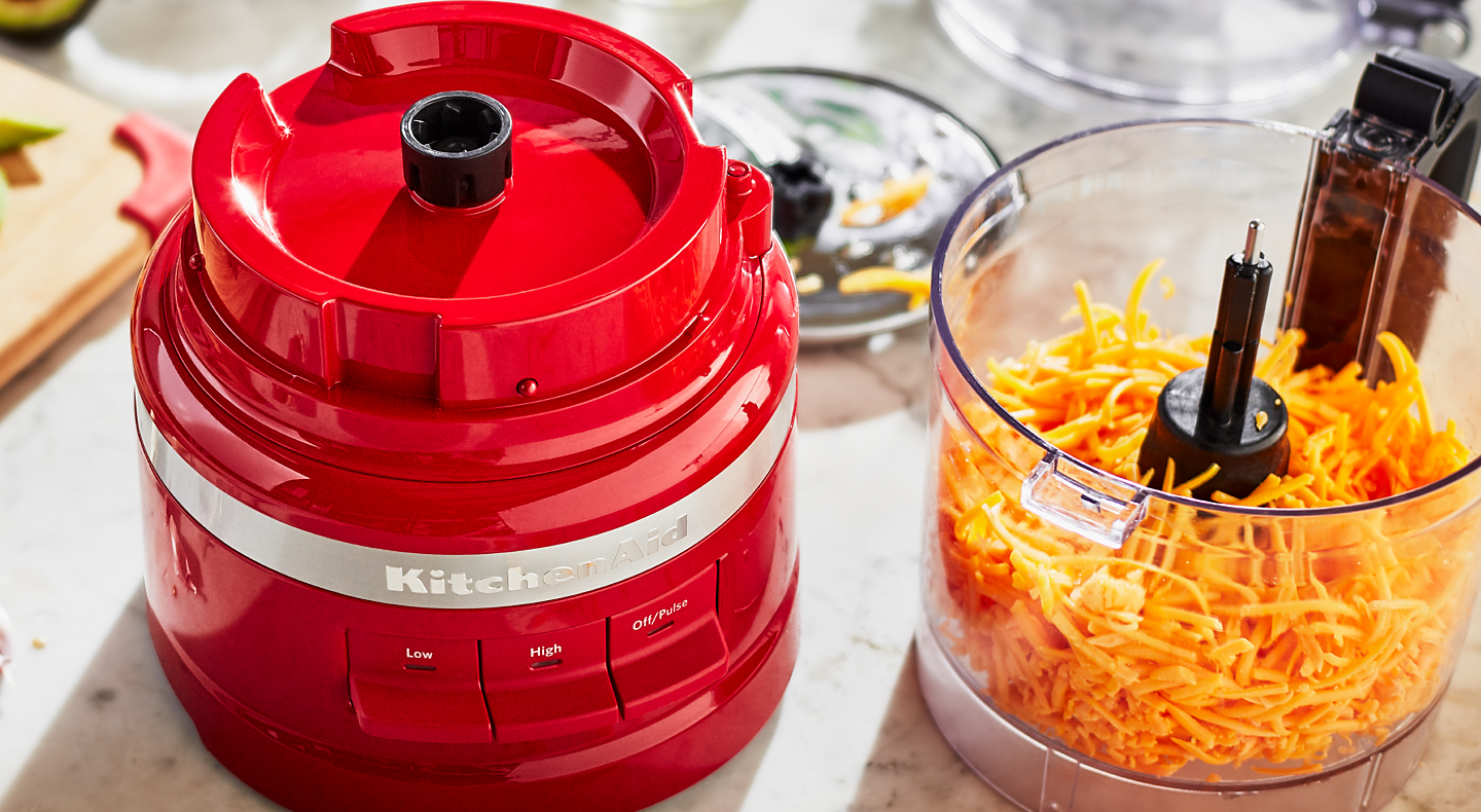 Red KitchenAid® food processor with shredded cheese in it