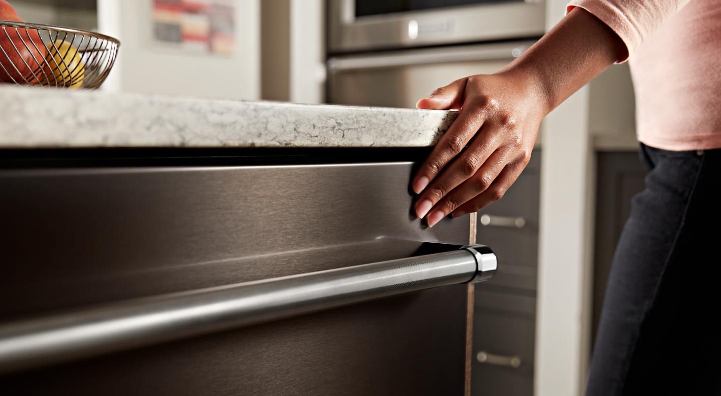 Person closing a KitchenAid® top control dishwasher