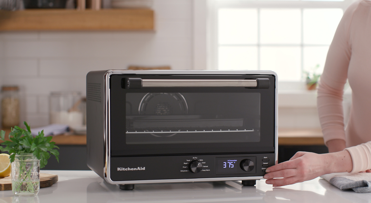 Person touching the console of a KitchenAid® countertop oven