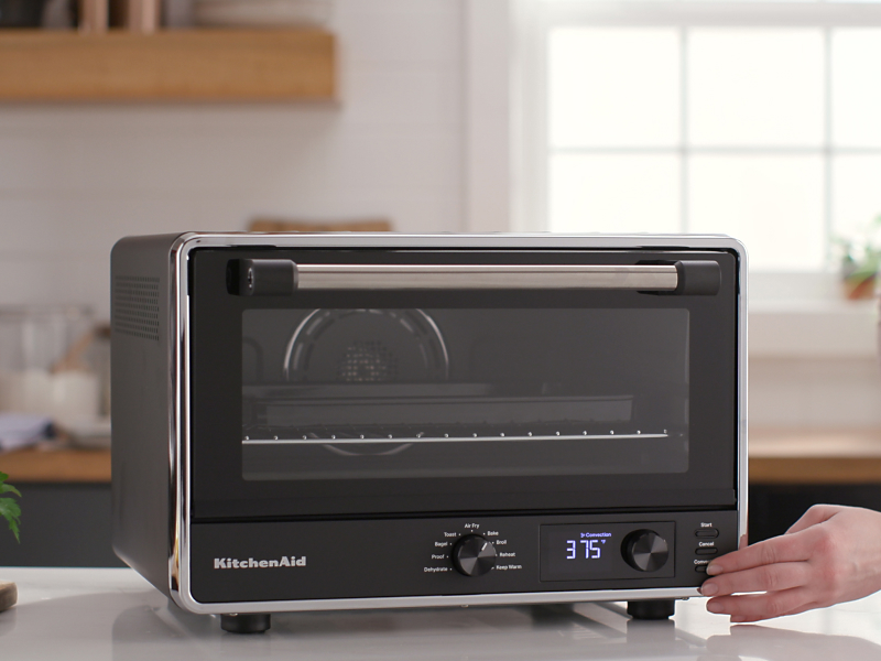 Person touching the console of a KitchenAid® countertop oven