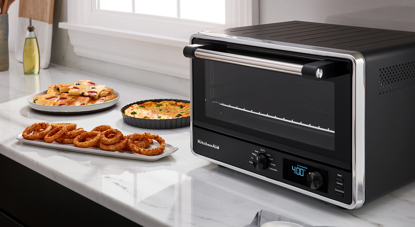 KitchenAid® countertop oven with onion rings on a tray