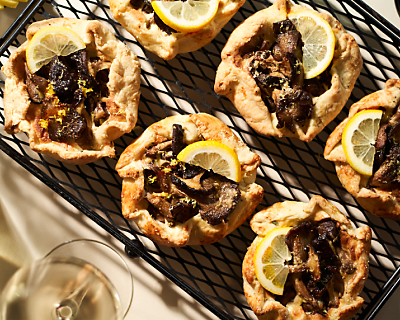 Savory mushroom galette topped with lemon wedges on wire cooling rack
