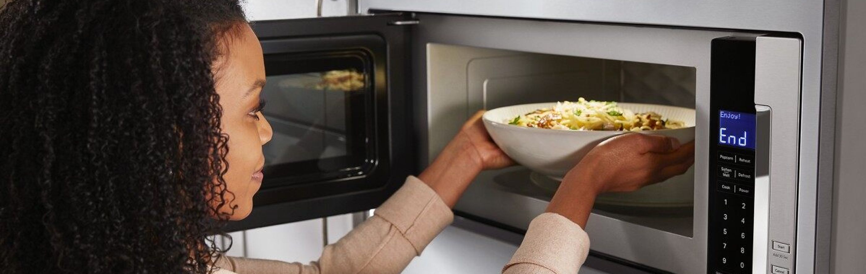 Person placing a bowl inside a built-in microwave