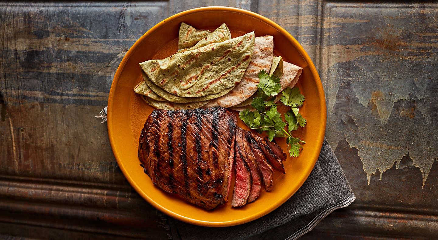 Sliced steak and fresh tortillas garnished with herbs