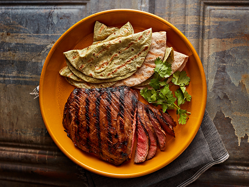 Sliced steak and fresh tortillas garnished with herbs