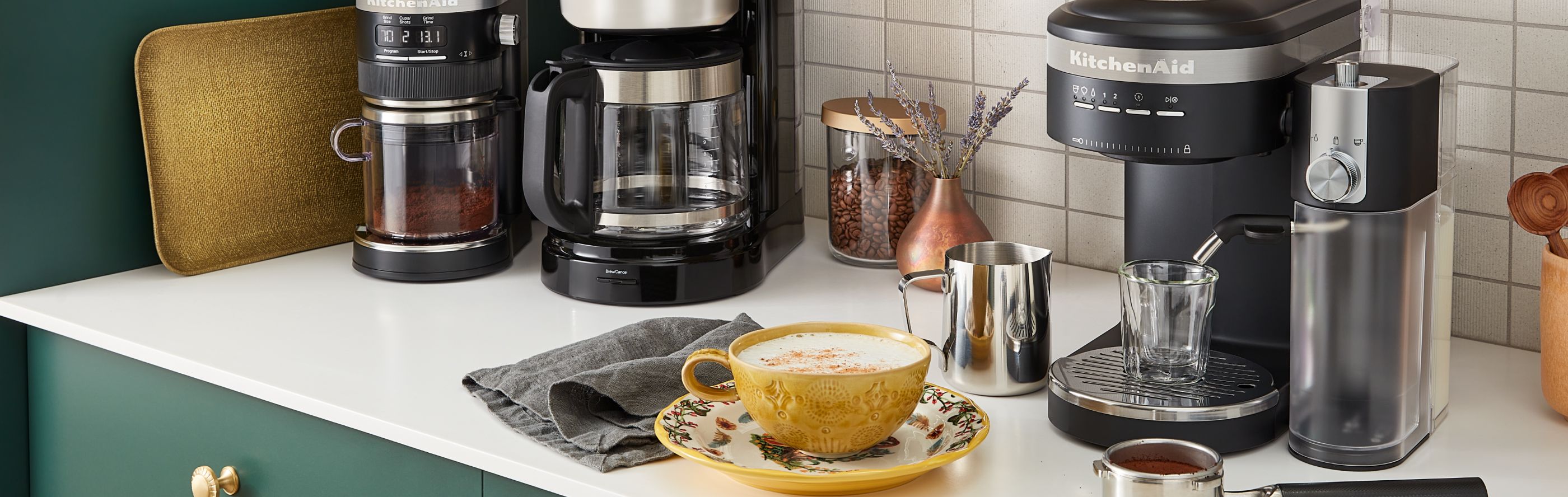 Latte in a yellow cup on white countertop next to KitchenAid® espresso machine