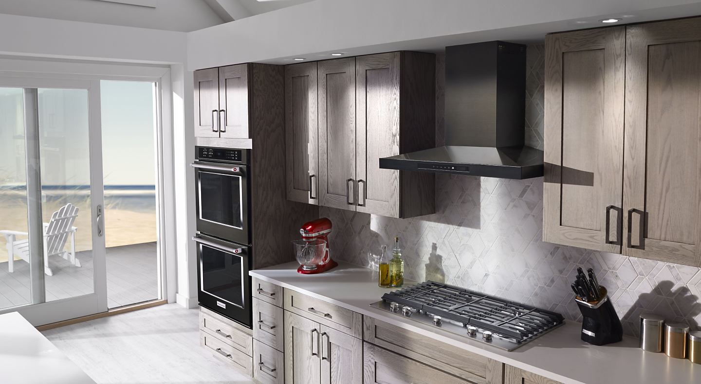 KitchenAid® wall mount range hood and gas cooktop and double oven in a kitchen