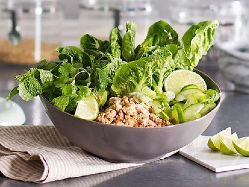 Lettuce salad with lime wedges in gray bowl on countertop