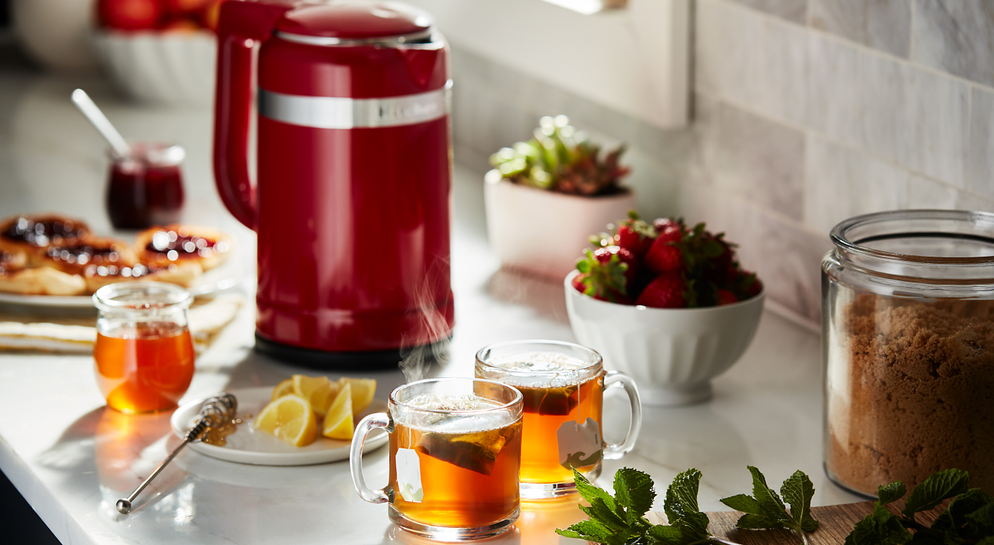 Red KitchenAid® kettle and cups of tea on a countertop