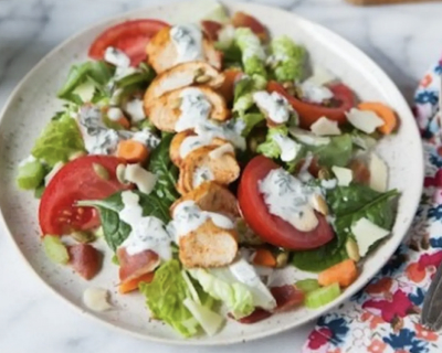 Leafy greens and tomato wedges drizzled with ranch dressing.