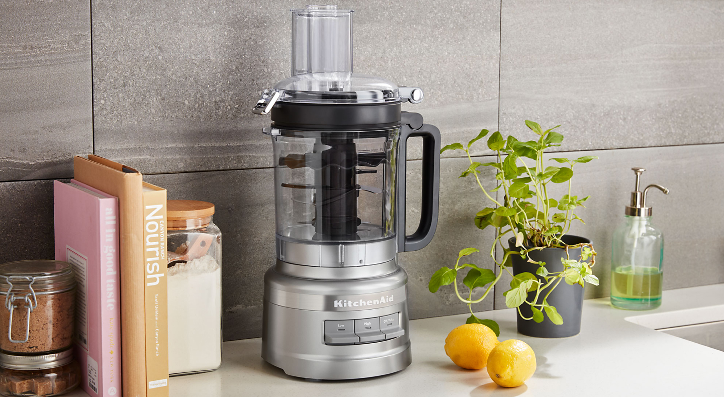 KitchenAid® food processor on countertop with cookbooks and canisters