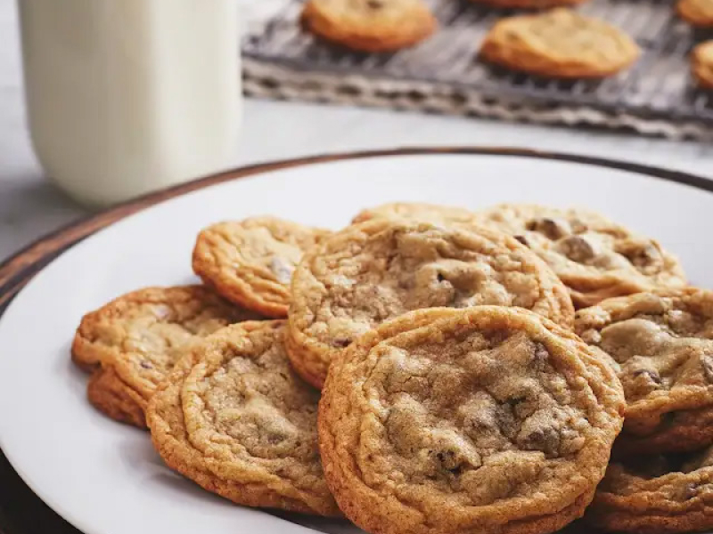 Baked chocolate chip cookies on a plate next to a cooling rack