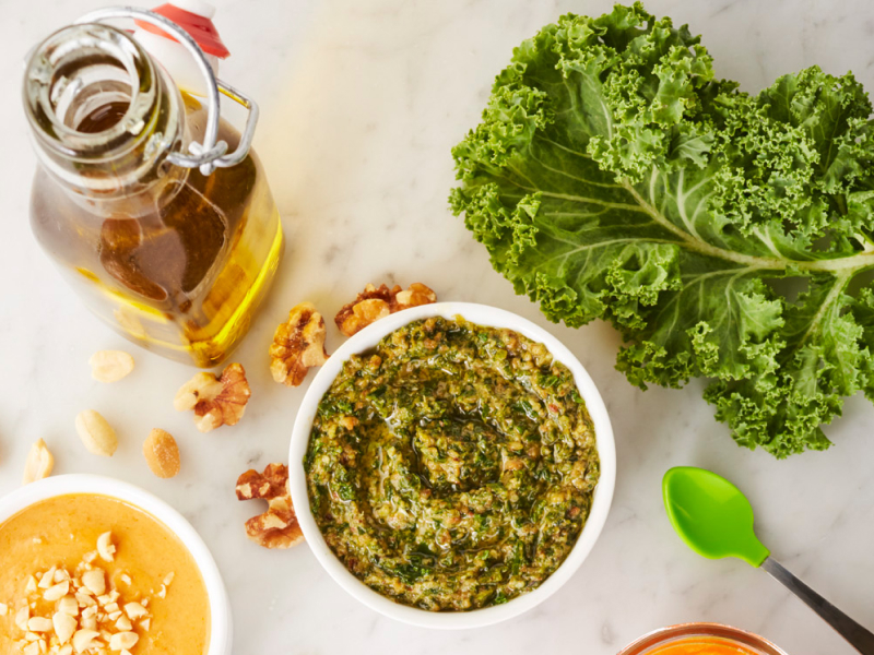 Homemade pesto next to a bottle of oil and kale