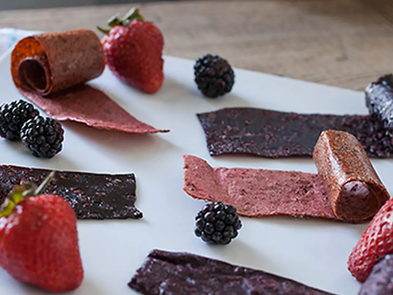 Sheets of homemade fruit leather and black berries.