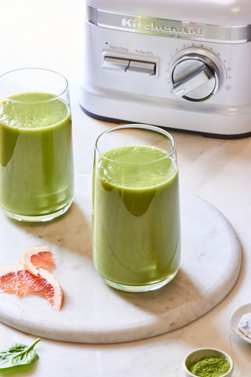 Green juice in glasses next to KitchenAid® blender