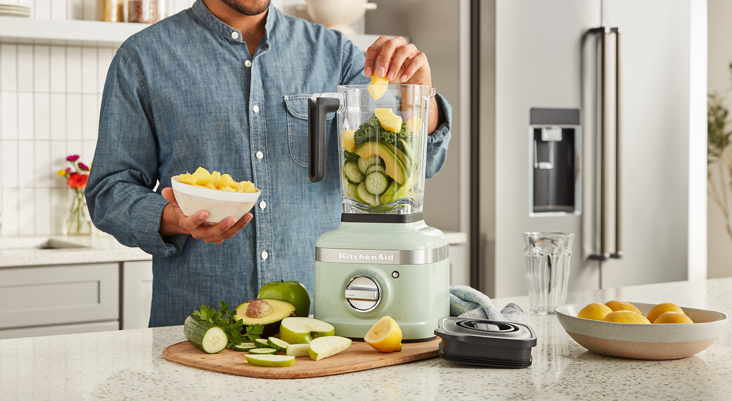 Person adding produce to a KitchenAid® blender