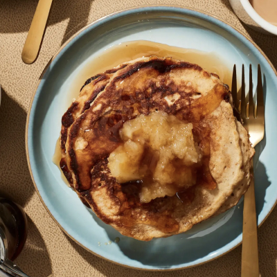 Birds-eye view of homemade pancakes topped with syrup and homemade applesauce