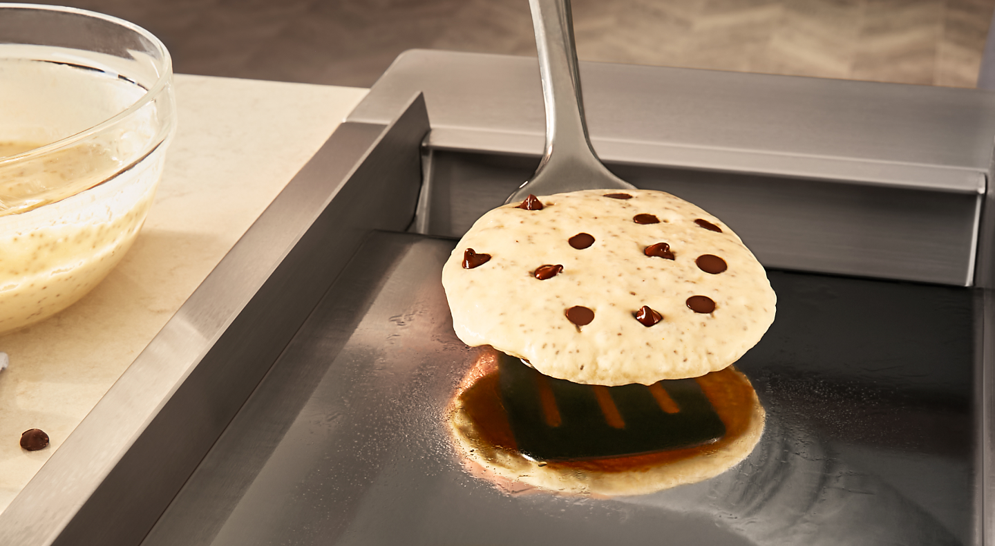 Person flipping chocolate chip pancake with spatula