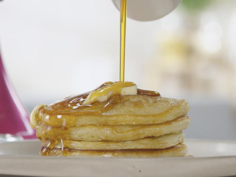 Syrup pouring over prepared stack of pancakes