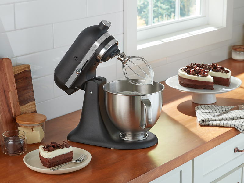 KitchenAid® stand mixer with wire whip next to cake
