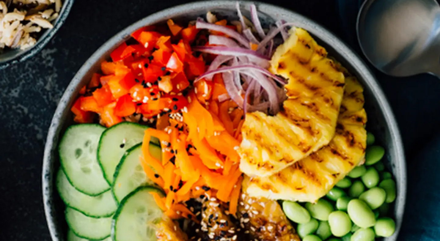 Birds-eye view of a poke bowl with red onion, tomato, cucumber and more