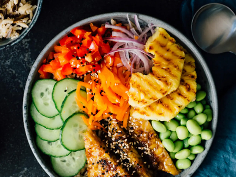 Birds-eye view of a poke bowl with red onion, tomato, cucumber and more