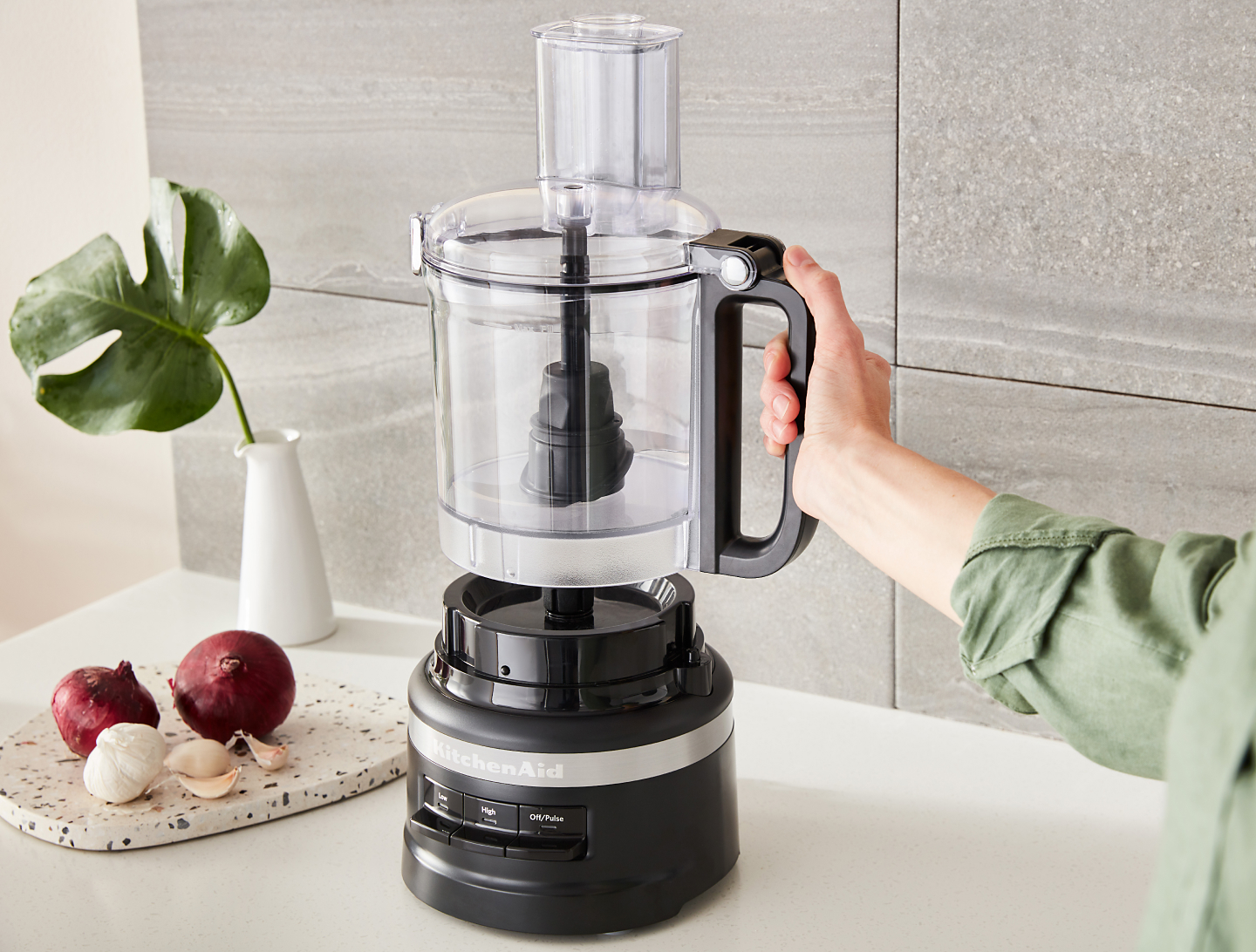 Person placing the work bowl of a black KitchenAid® food processor onto the base