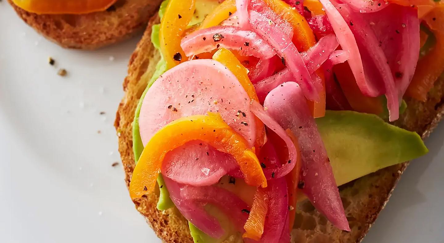 Pickled red onions on top of toast with avocado and other veggies